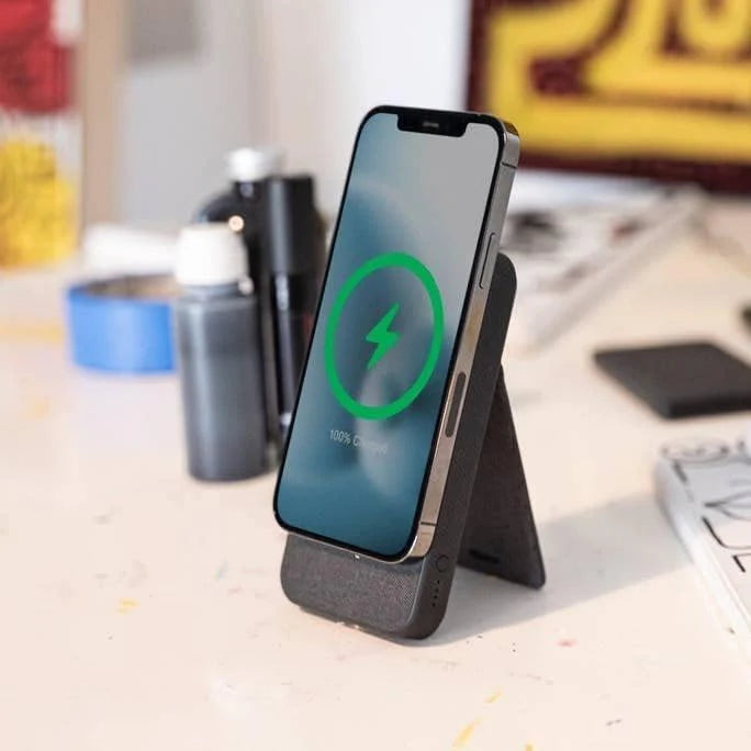 Phone on a stand with charging icon on screen, blurred office background