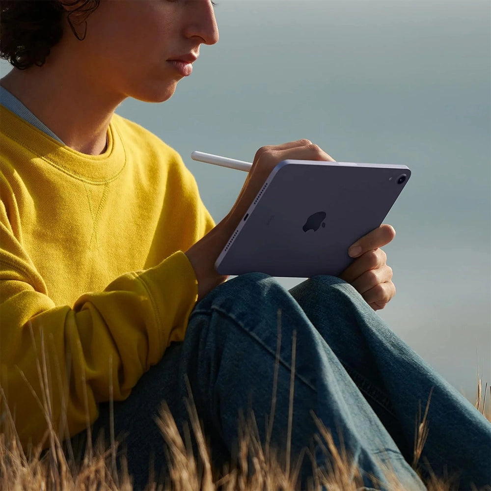Person holding a purple tablet with a stylus in a natural setting