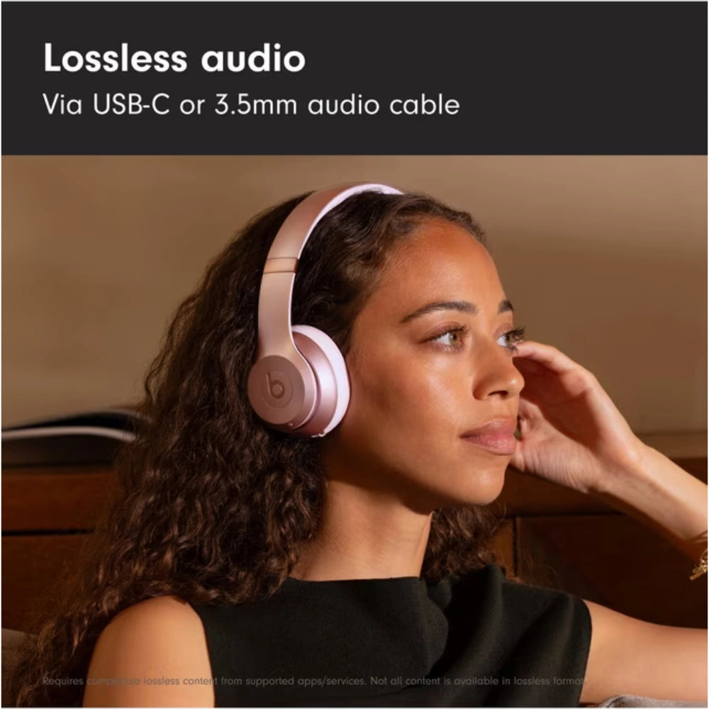 Woman wearing pink Beats headphones with text about lossless audio via USB-C or 3.5mm cable.