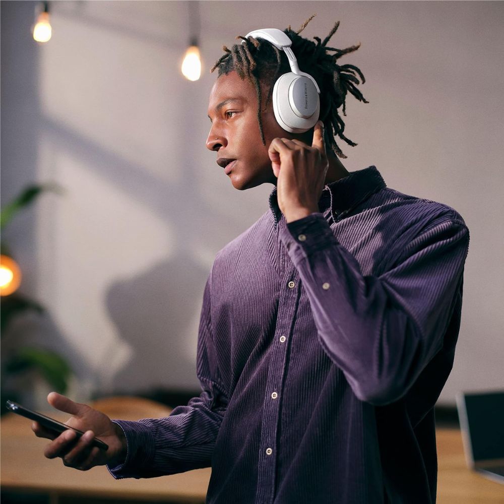Man wearing headphones and holding a phone in a modern indoor setting