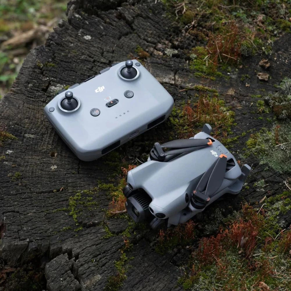 DJI Mini 5 pro drone and controller on a wooden surface with moss